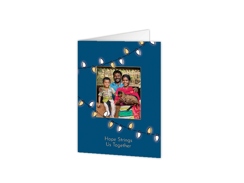 Front cover of a holiday honor card featuring a family and holiday lights on a blue background.