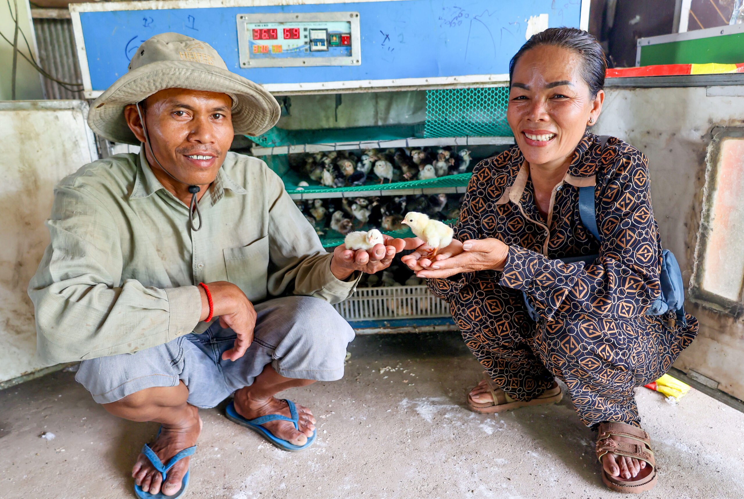 A woman and a man crouch in front of an incubator.