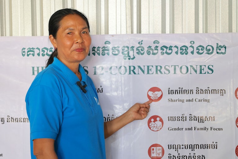 A woman points to a poster of Heifer’s 12 Cornerstones.