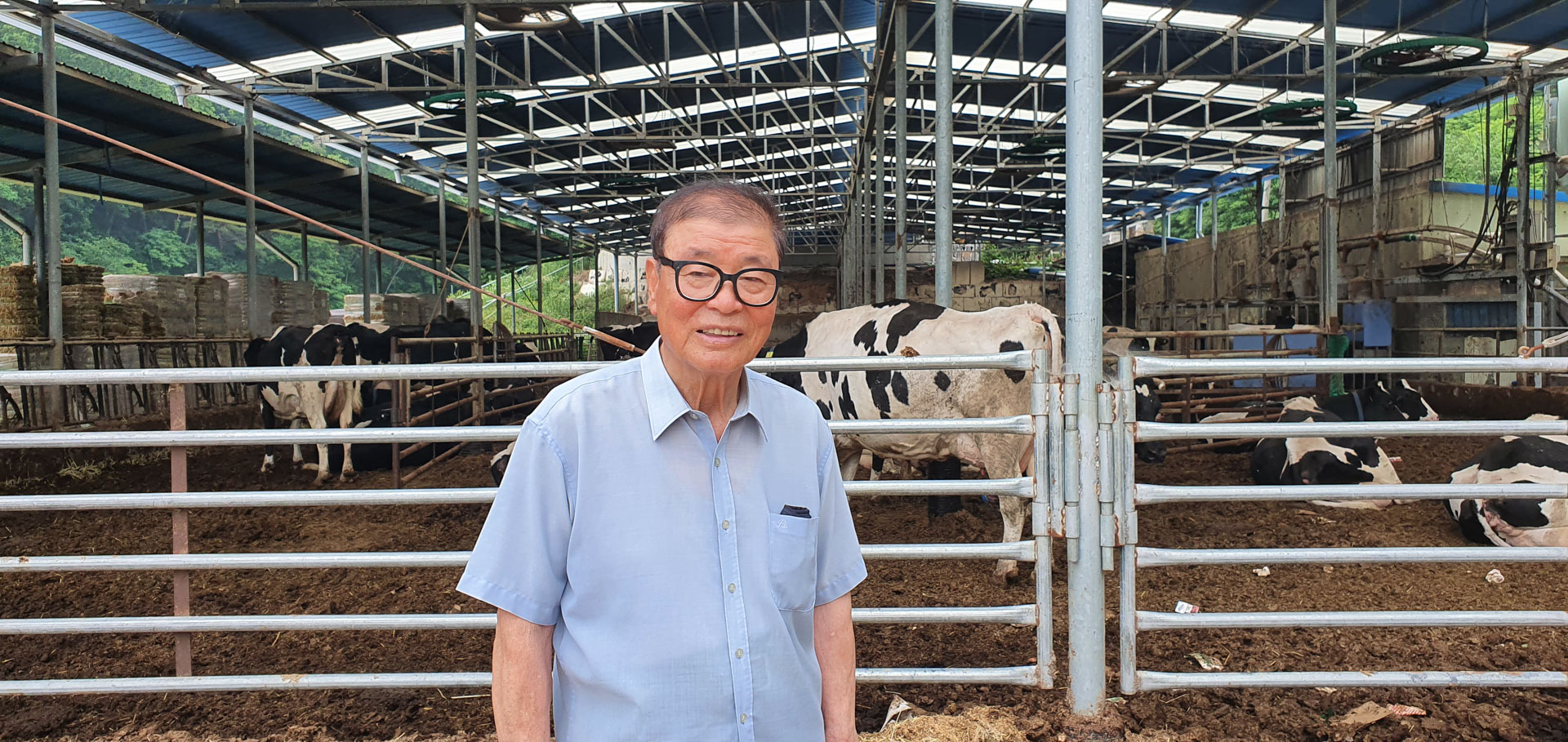 A man stands in front of cows at his dairy farm.