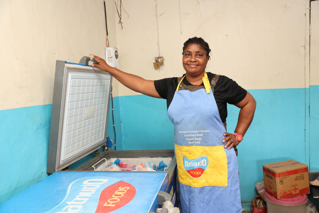A woman stands beside a solar-powered freezer.