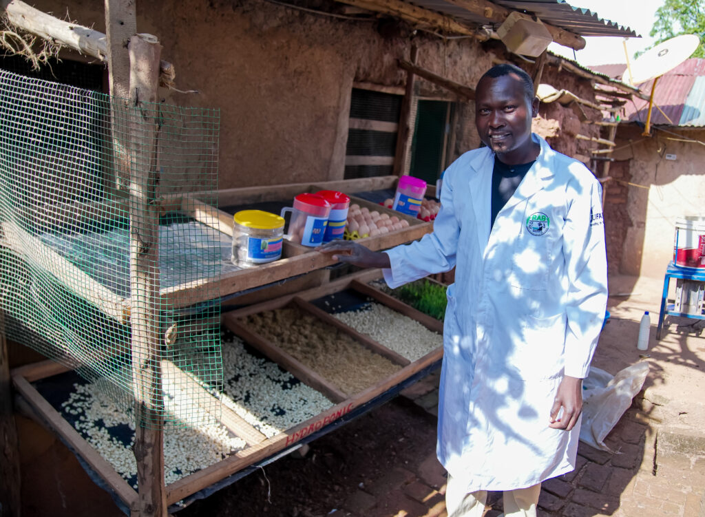 A man stands beside eggs and packaged Azolla feed at a cooperative facility.