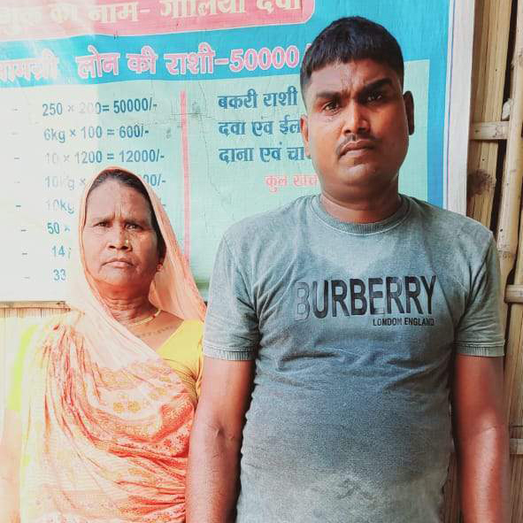 An Indian woman wearing a sari stands next to an Indian man in a gray t-shirt.