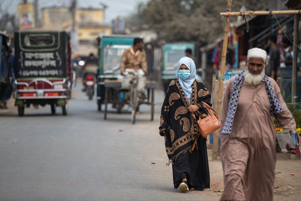A woman walks toward the camera on a busy street in Bangladesh.