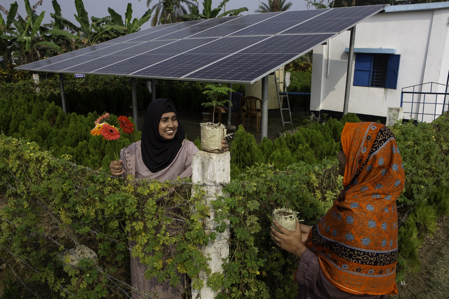 Asma Khatun, 36, (left) talks to Zahirul Islam at a solar panel site in Panisara village, Bangladesh