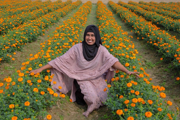A woman smiles in a marigold field.