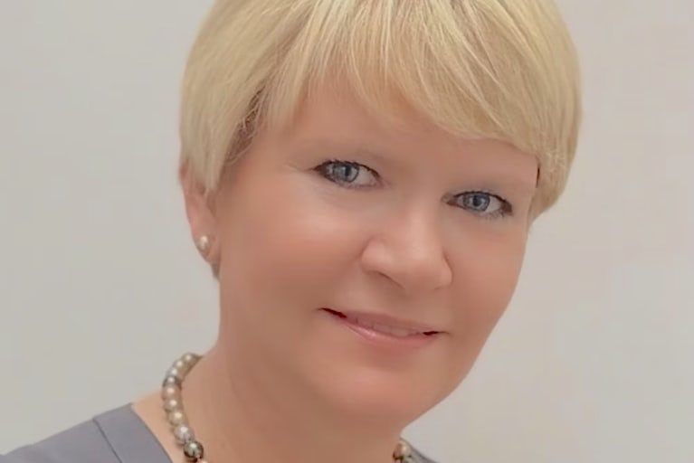 Headshot of Babsi Snowden wearing a gray shirt and multi-colored pearl necklace