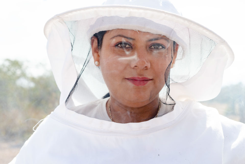 A portrait of Honduran woman wearing a beekeeping suit.