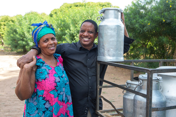 Josephine Mutuku and Joseph load milk containers onto a motorcycle bound for market.