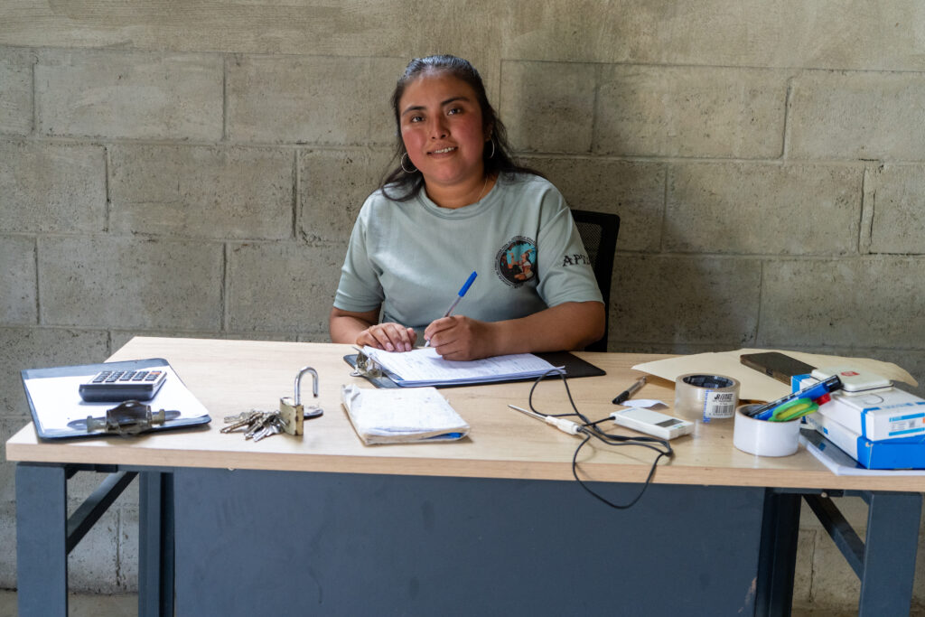 A woman writes on paperwork at a desk.