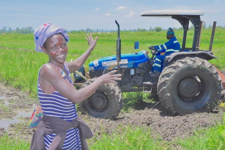 A woman standing in front of a tractor in a field