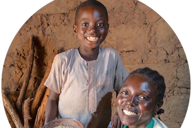Woman and child smiling while holding a bowl of rice grains