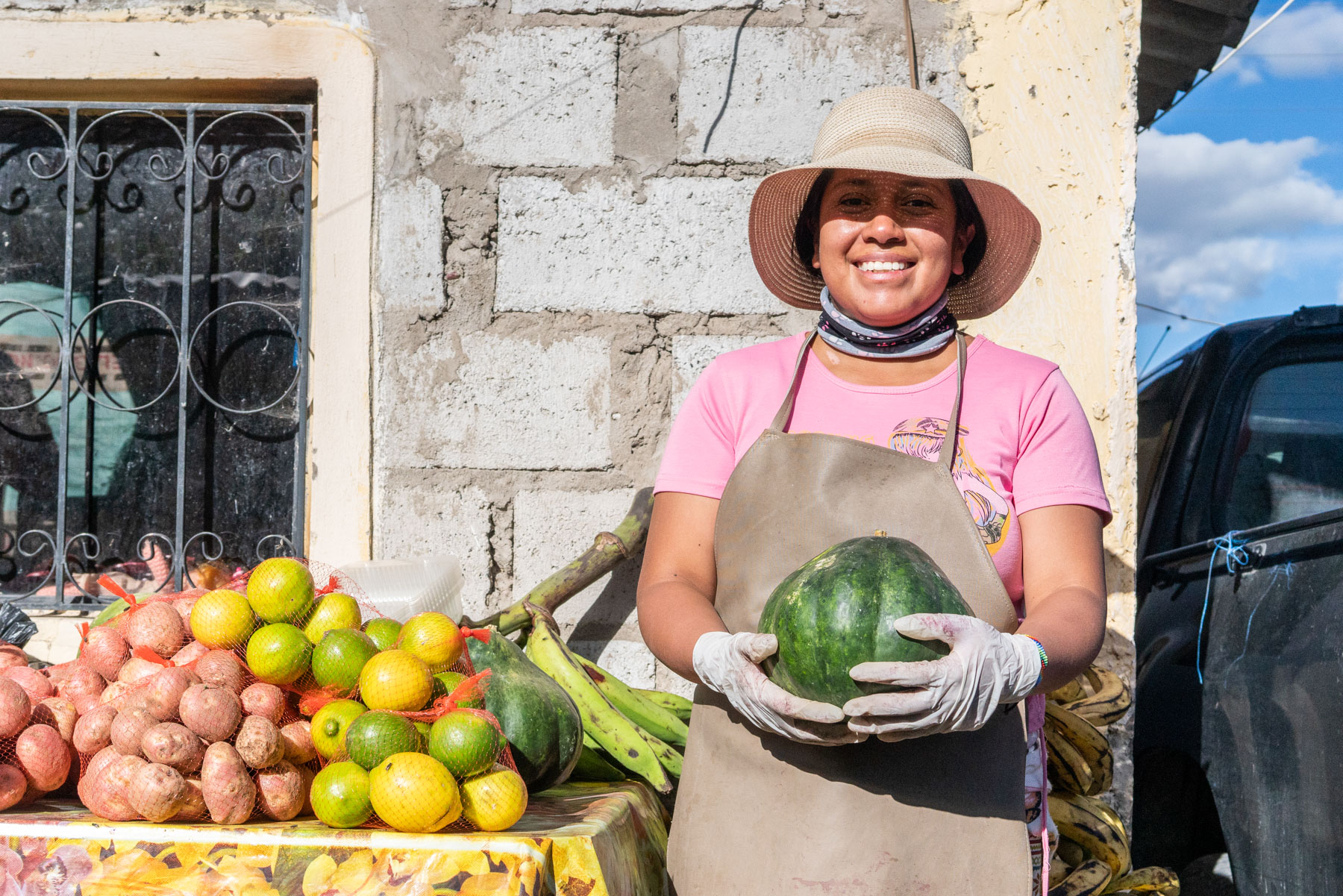 A woman smiles while holding a watermelon.