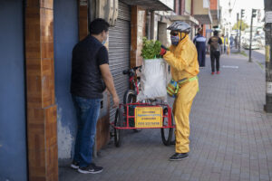 A member of La Changa Collective delivers fresh produce to a customer's doorstep while using personal protective equipment provided by Heifer. 