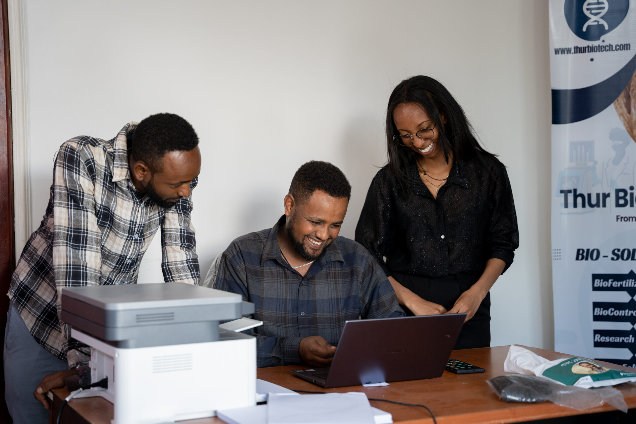 A group of colleagues review biofertilizer research on a laptop in an office.