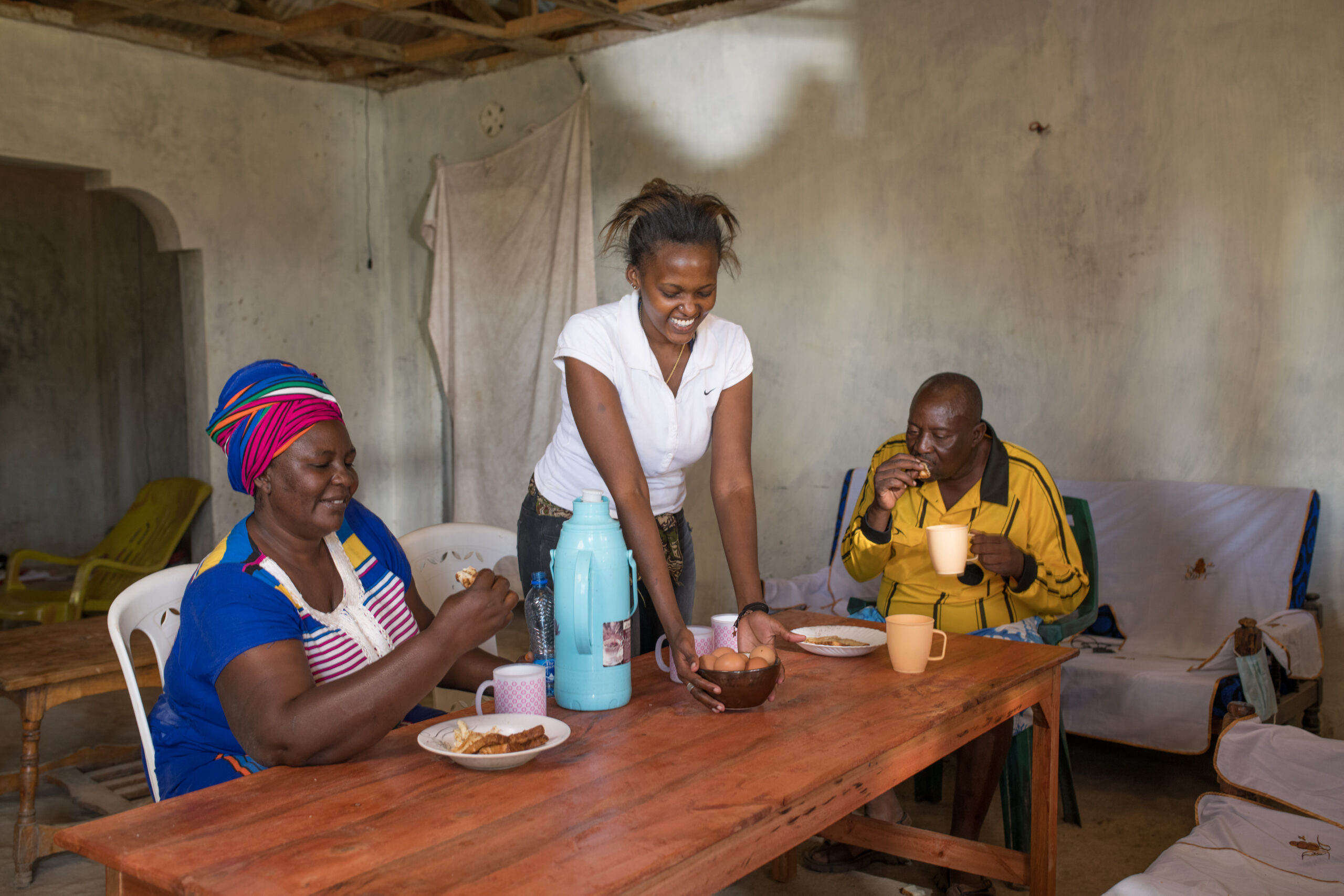 A woman, her daughter and her husband sit at a table eating eggs.
