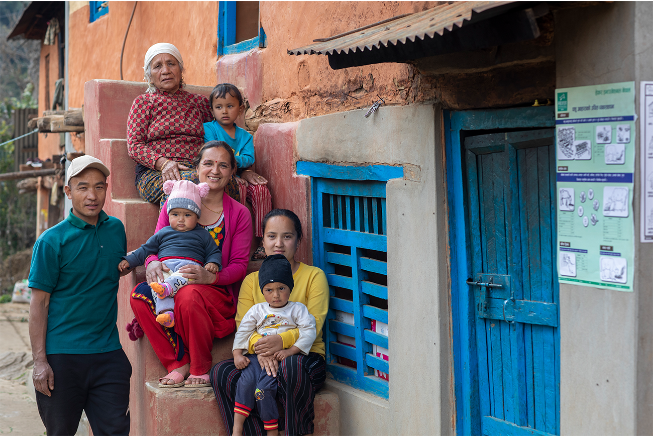 A family of seven sit together on some steps.