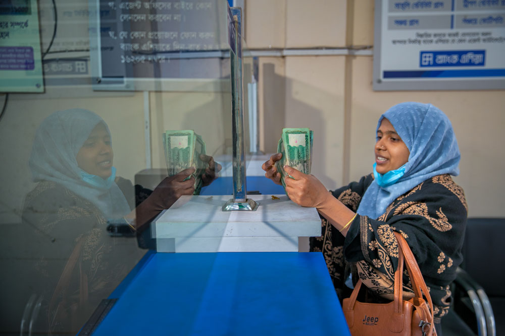 A woman at a bank counter happily exchanges money.