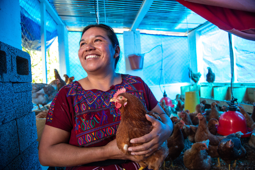 Juana holds a chicken in the family's coop.