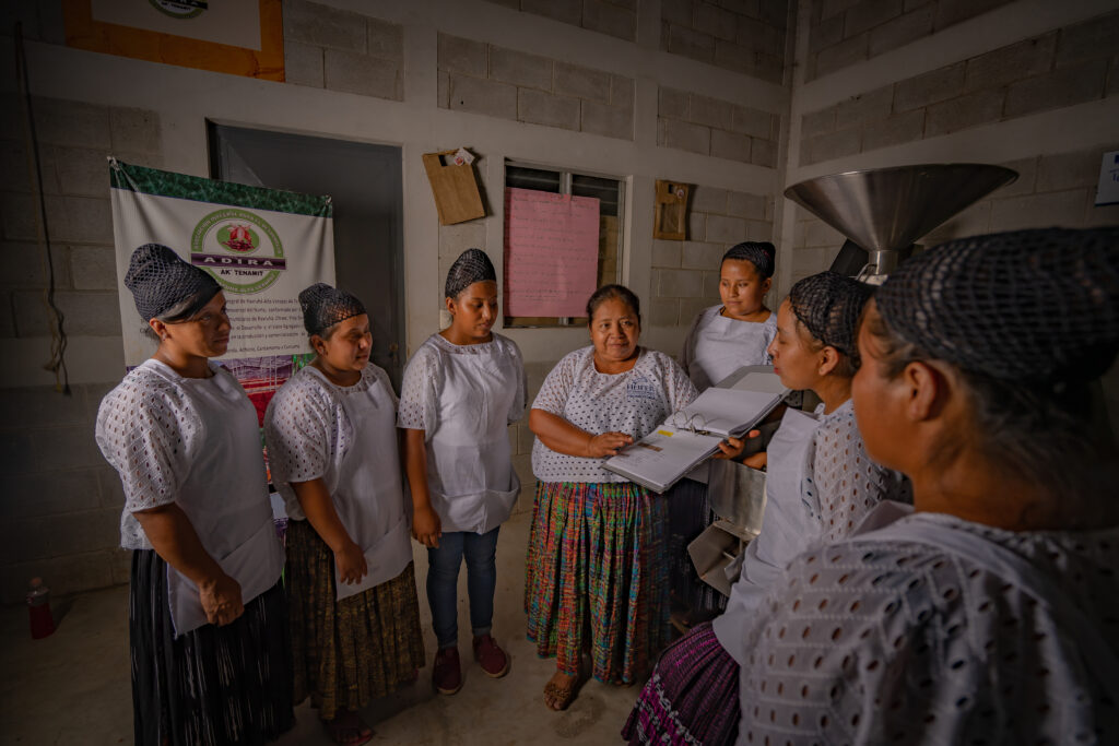 A woman leads a discussion with members of the ADIRA cooperative.