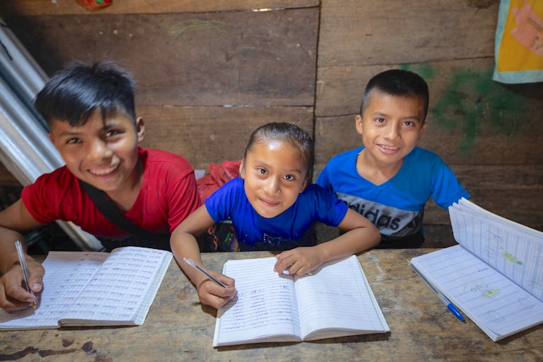 Children smile while working on their homework.