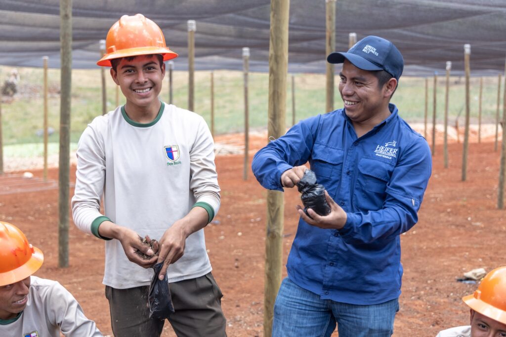 Henry Choc Xol smiles and Heifer staff member Braulio Paau shows him how to prepare bags of soil for seedlings.