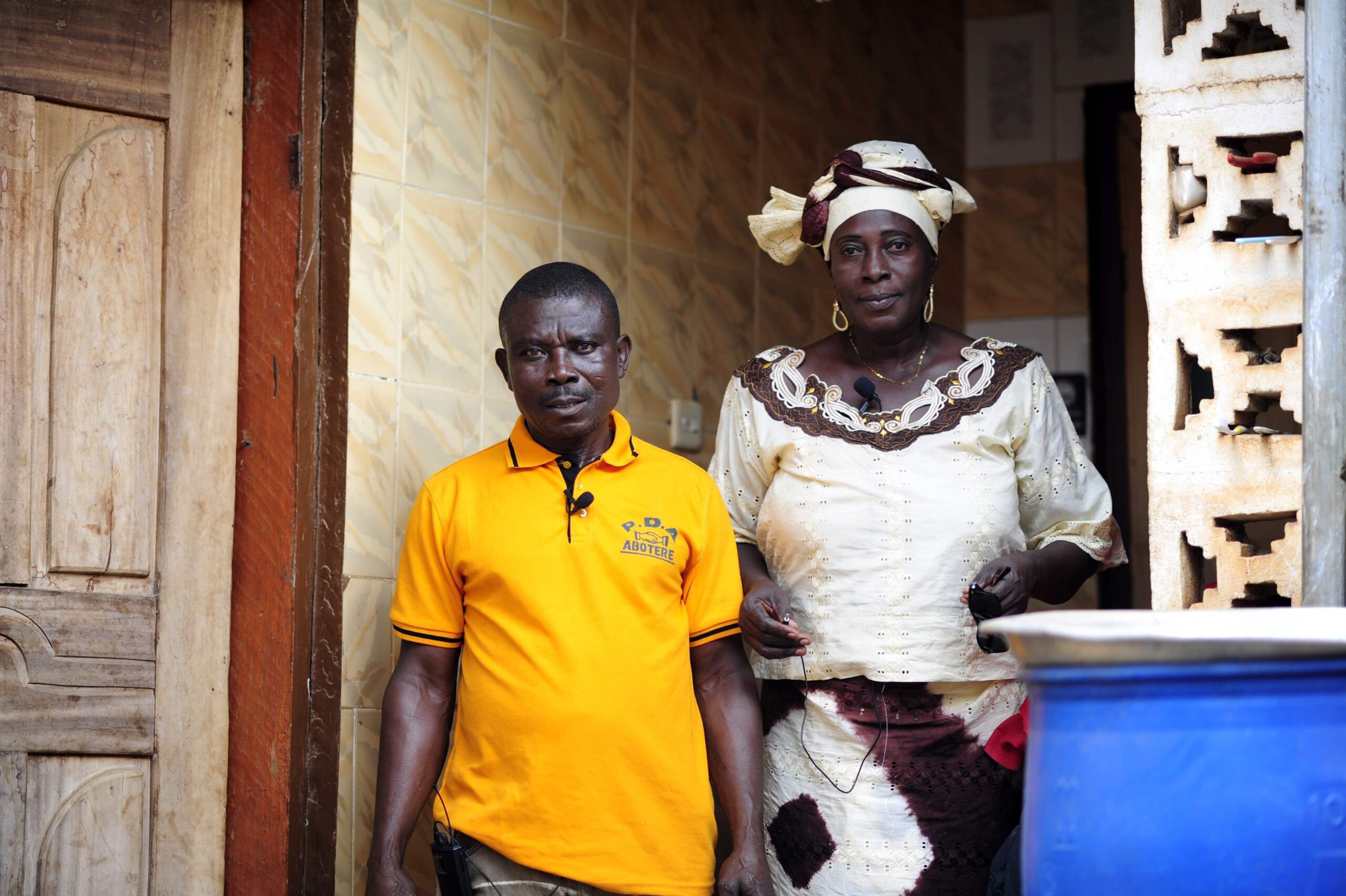 Rose stands beside her husband in the entryway of their home in Ghana