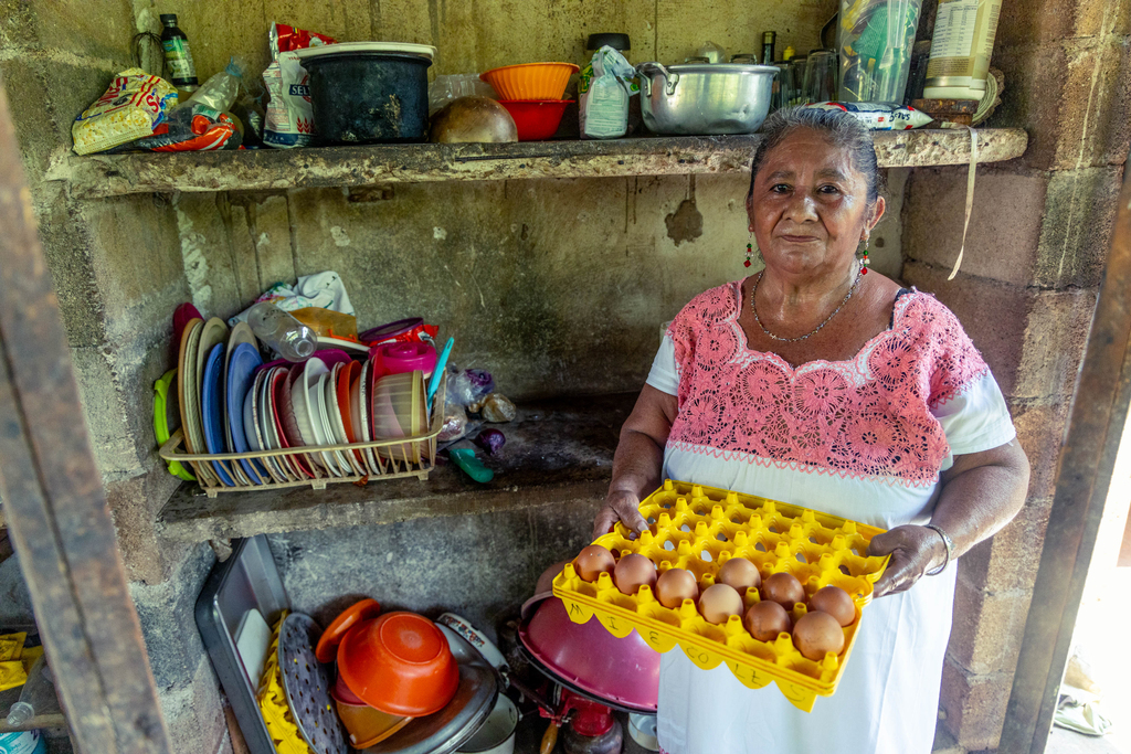 A woman holds a tray of eggs.