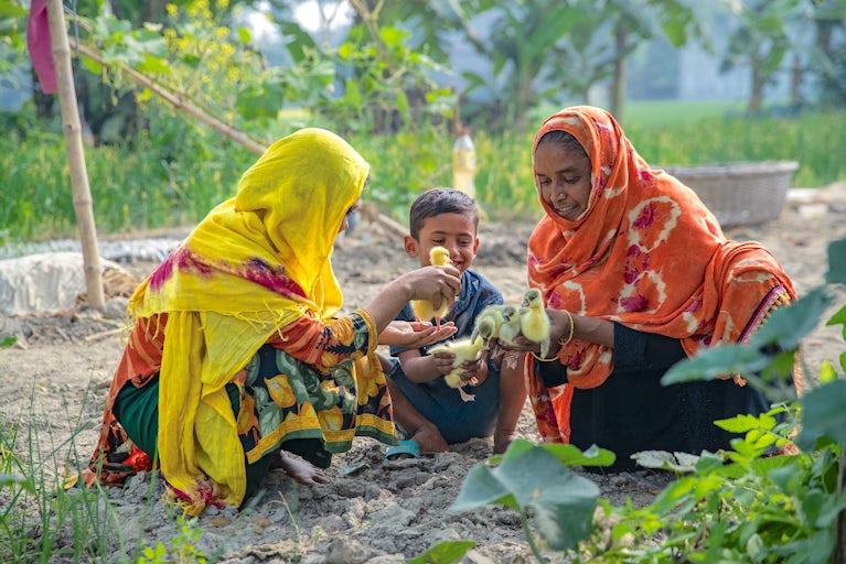 Two women and a child holding chicks.