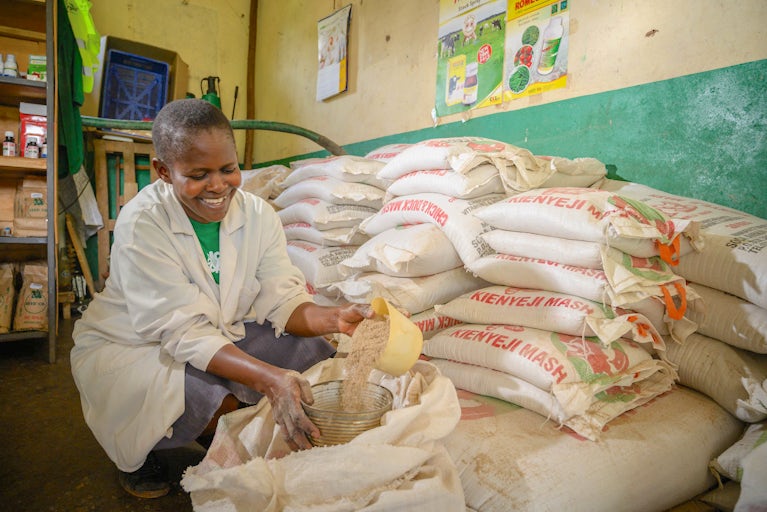 Christine Okode inside her agrovet shop packing some chicken feeds for a customer.