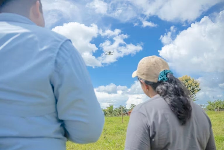 A man and woman in a field flying a drone camera.