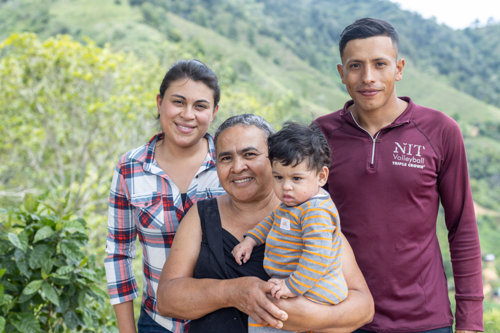 A portrait of a Honduran family, including a young woman, a woman holding a baby, and a young man.