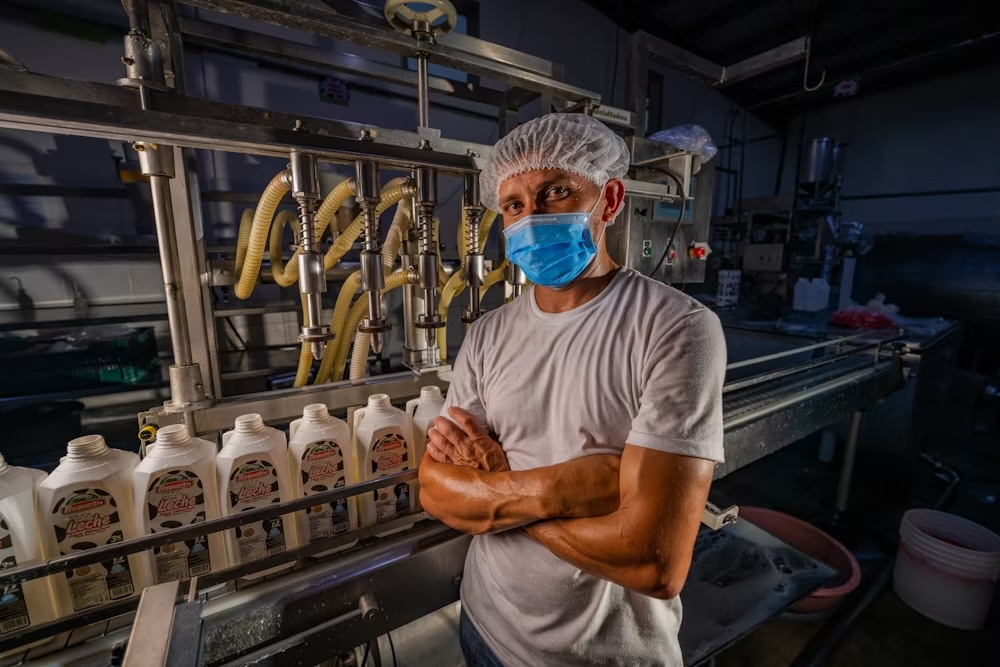 A man stands in front of a milk processing line in Honduras.