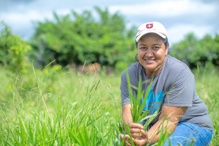 Keyla Aparicio holds and inspect a handful of grass from the pasture.
