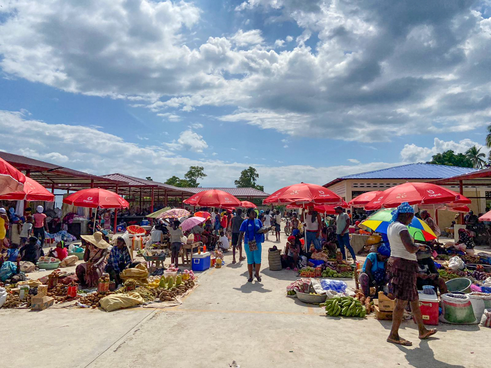 Numerous vendors sell their goods at a market in Haiti on a sunny day.
