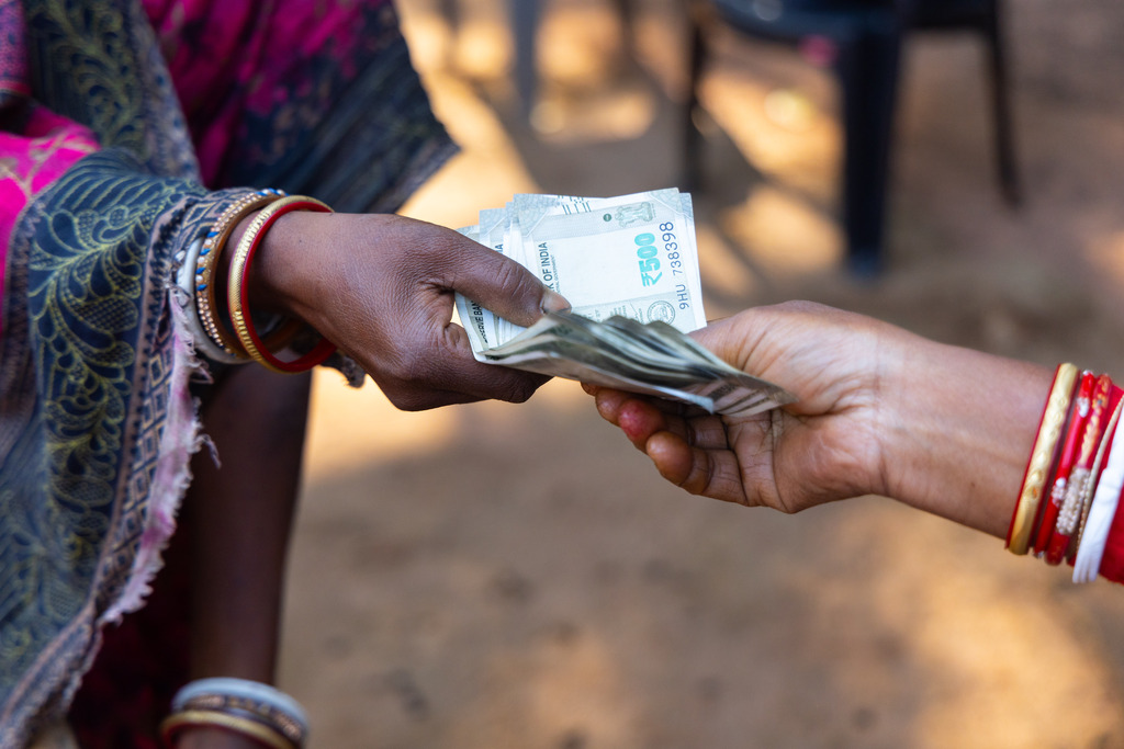 Hands exchange cash after a goat sale in Odisha, India.