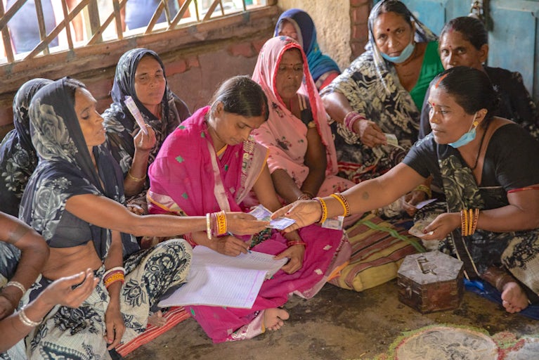 Group of women sitting in a circle and exchanging money.