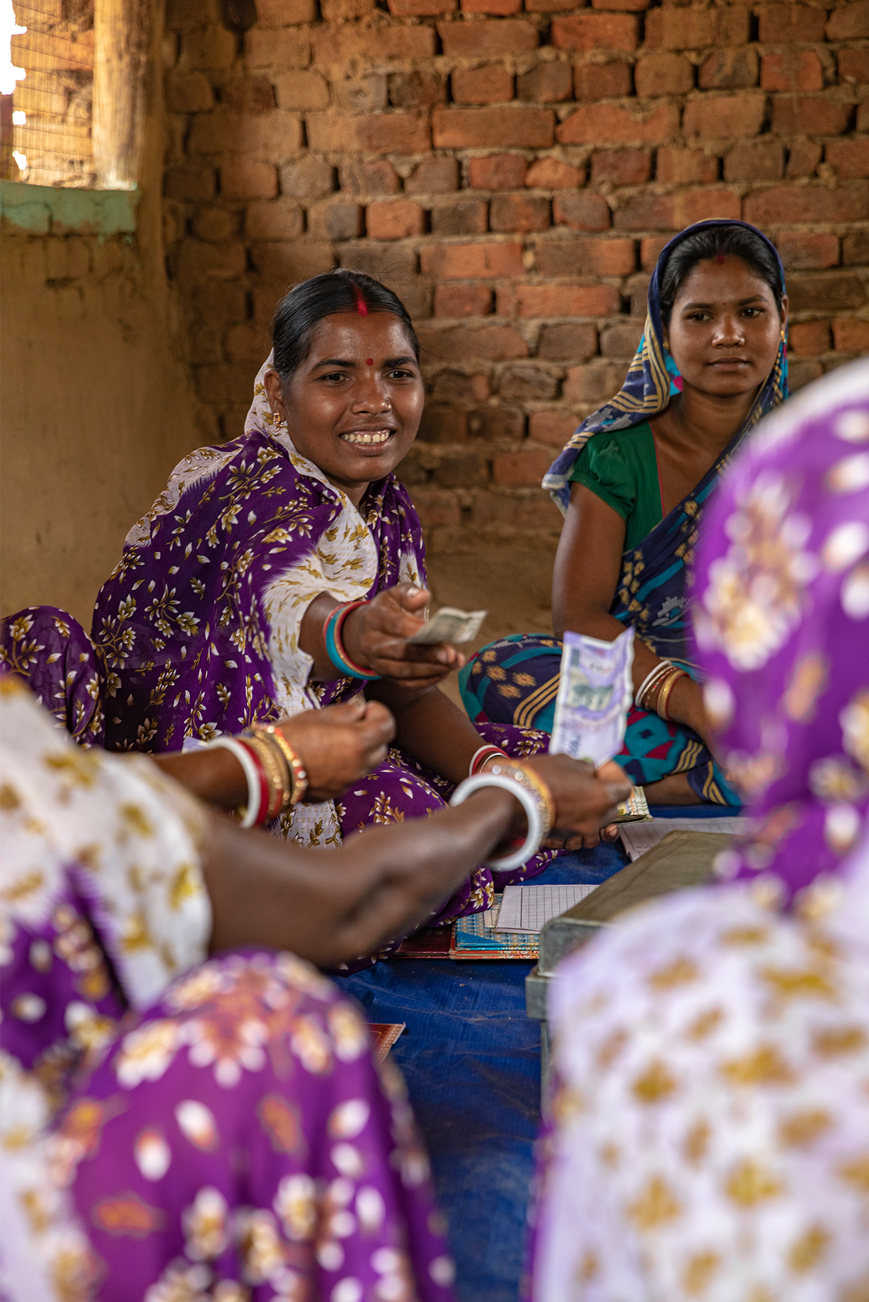 A woman hands money to a fellow group member.