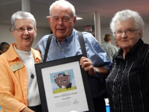 Three volunteers hold a framed award.