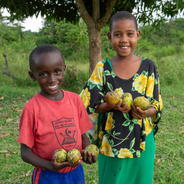 Johnson and Peace hold fruit in Uganda.