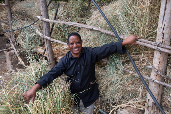 Joseph stands near at storage of different grasses he uses as fodder for his dairy cows.