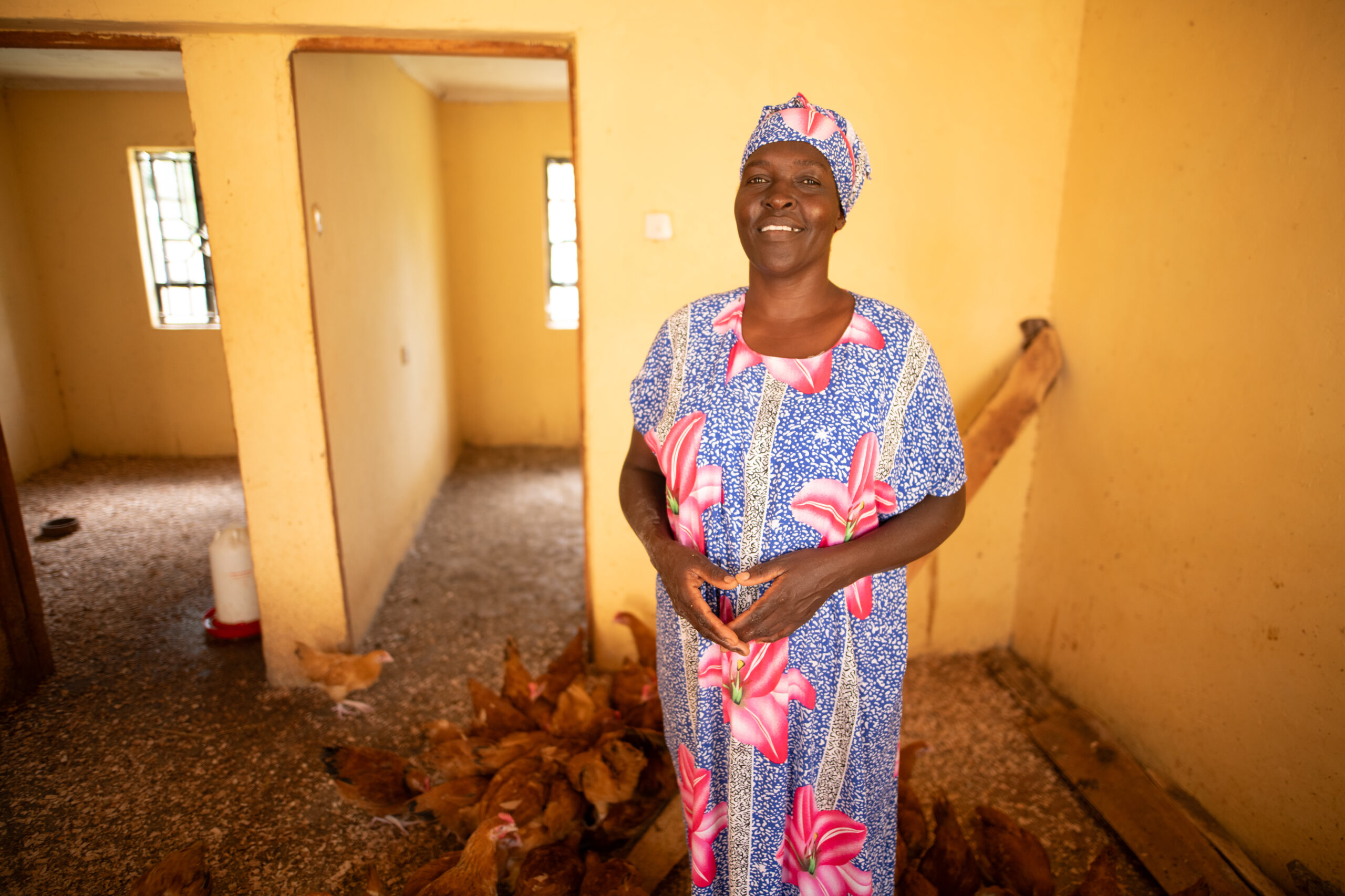 Woman smiles among a flock of chickens.