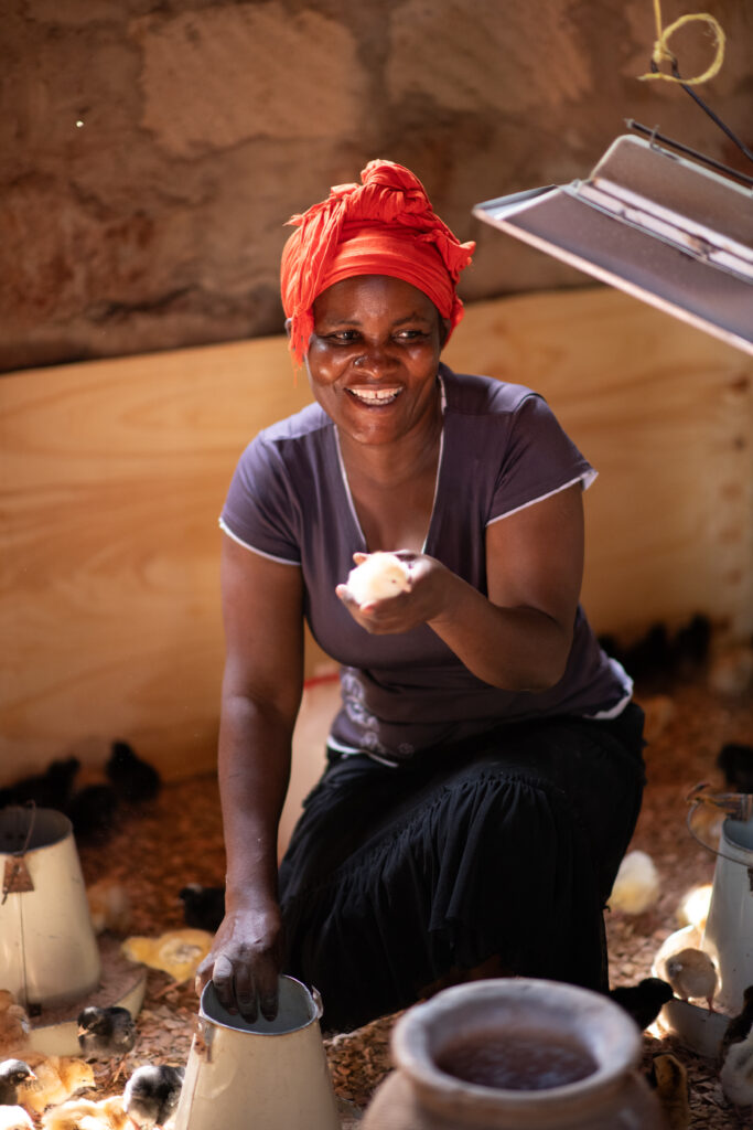 Woman smiles and tends chicks.