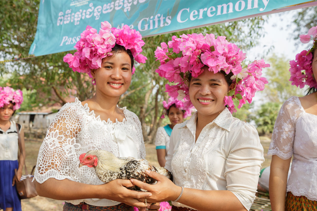 Sen Tos, 27, (left) and Phe Re Munh, 33, pose for a picture holding a symbolic pass on chicken during a Passing on the Gift ceremony.