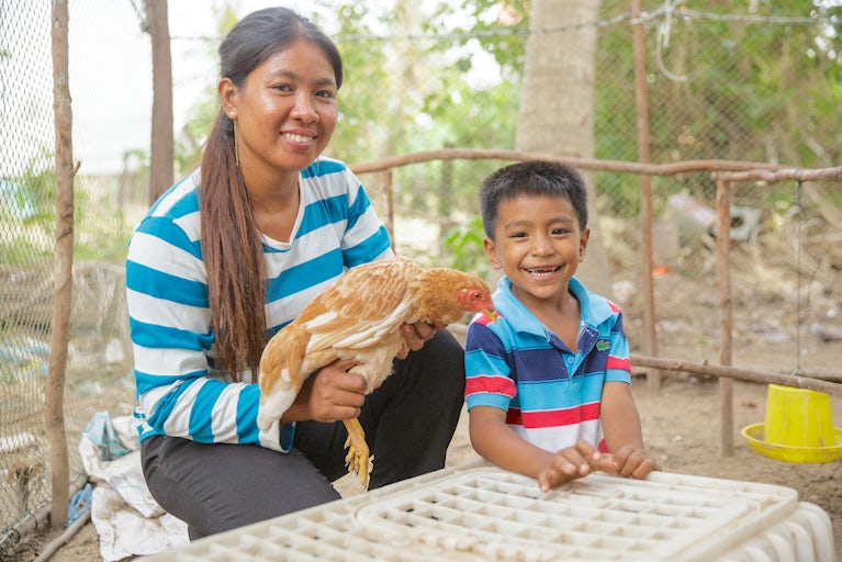 Woman holding chicken with child.