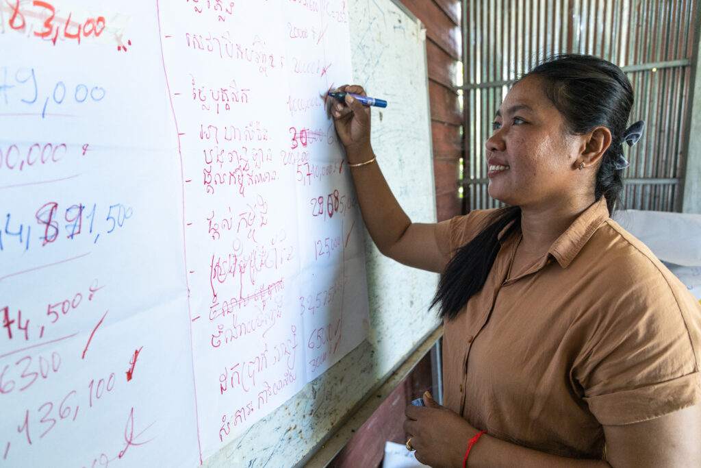 Set Hach writes figures on a whiteboard covered with Khmer text and numbers.