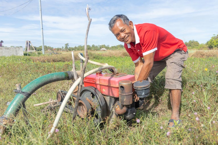 Sun Sythol starts a gas water pump to irrigate his green onion fields.