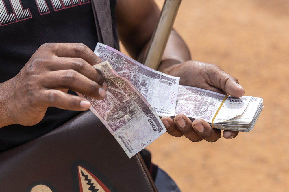 Close-up of hands holding a bundle of banknotes.