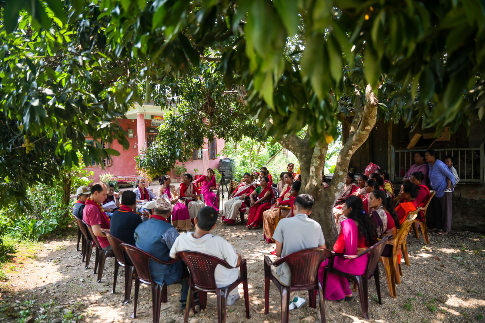 Women sitting in a circle outdoors during a cooperative meeting.
