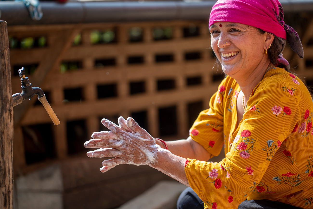 A Nepali woman checks her tablet, while sitting on a bed.